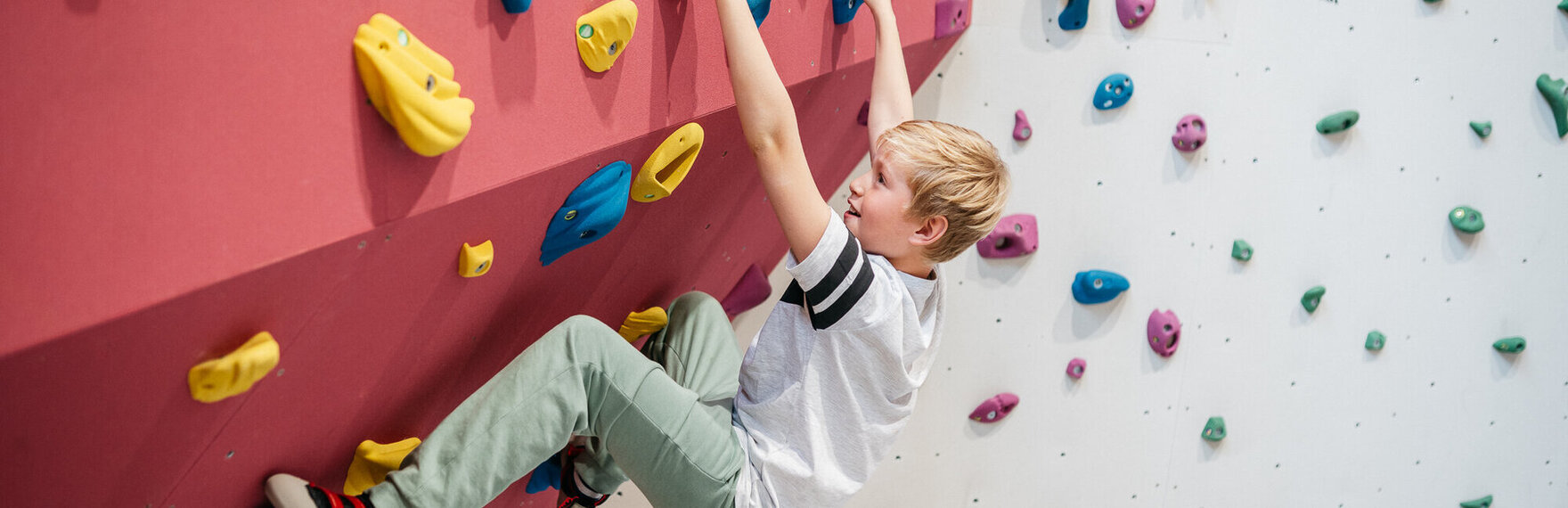 Ein Junge klettert an einer Indoor-Kletterwand