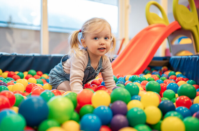 Ein Mädchen spielt im bunten Bällebad eines Kinderhotels.