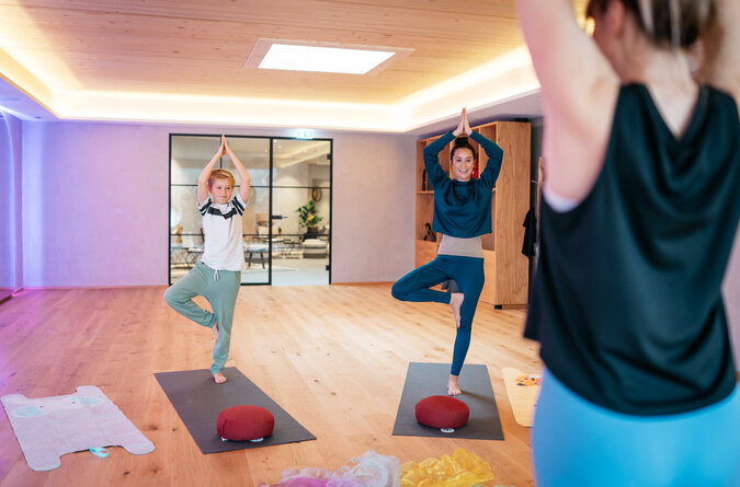 Mutter und Sohn machen Yoga mit einer Trainerin in einem Kinderhotel.