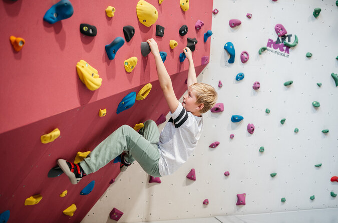Ein Junge klettert an einer Indoor-Kletterwand